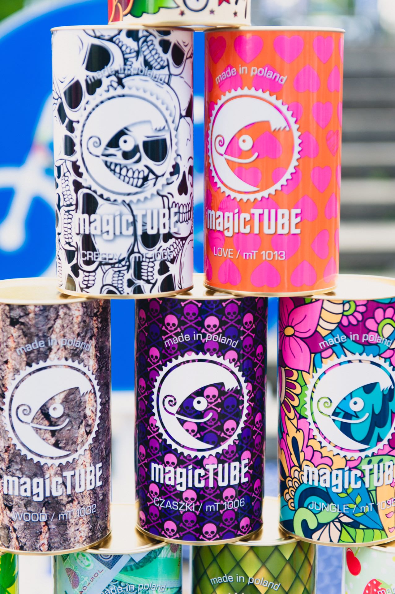 A colorful display of cylindrical tubes labeled "magicTUBE" arranged in a pyramid, captured by the event photographer. The tubes feature designs such as skulls, hearts and psychedelic patterns. Each tube is labeled with "made in Poland" with style names such as "LOVE" and "JUNGLE," which is perfect for photo coverage of the fair.  