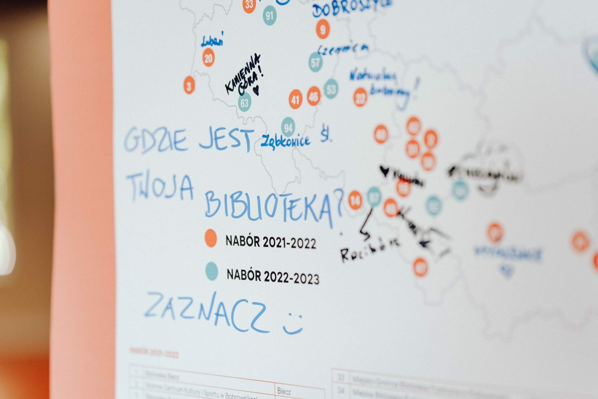 A close-up image of a map with handwritten notes, circles and colored markers. The map is titled "WHERE IS YOUR LIBRARY?" and marks the 2021-2023 enrollment period with the word "ENTER" followed by a smiley face. Blue and orange colors mark the various locations, creating a perfect photo-relation of the  