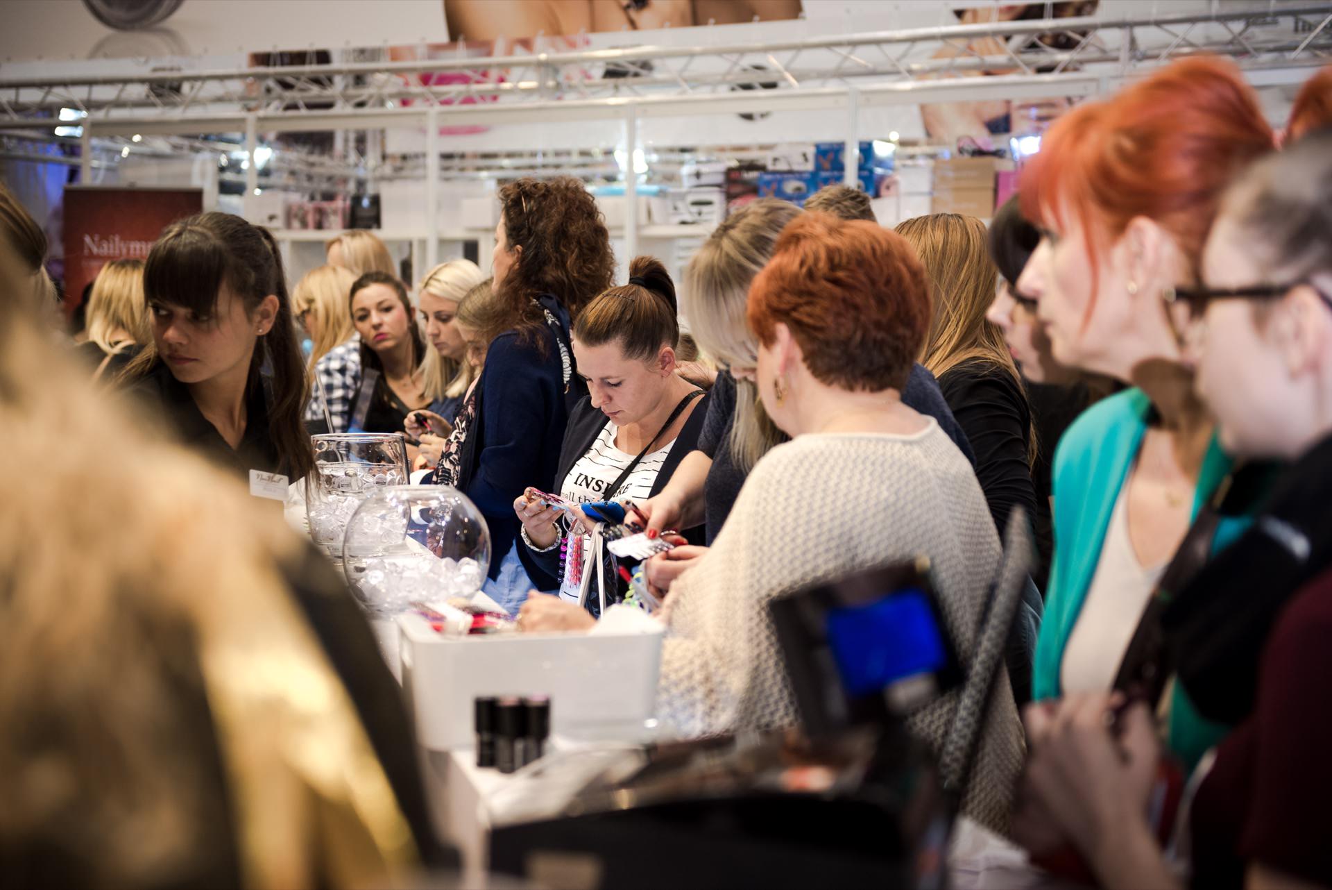 A large group of people, mostly women, gather at a busy party or workshop in a room. They are engaged in various activities, such as looking at objects on the table, writing and talking. The atmosphere is lively and focused, and event materials and decorations are visible - perfectly captured by Marcin Krokowski, a talented photographer in Warsaw.  