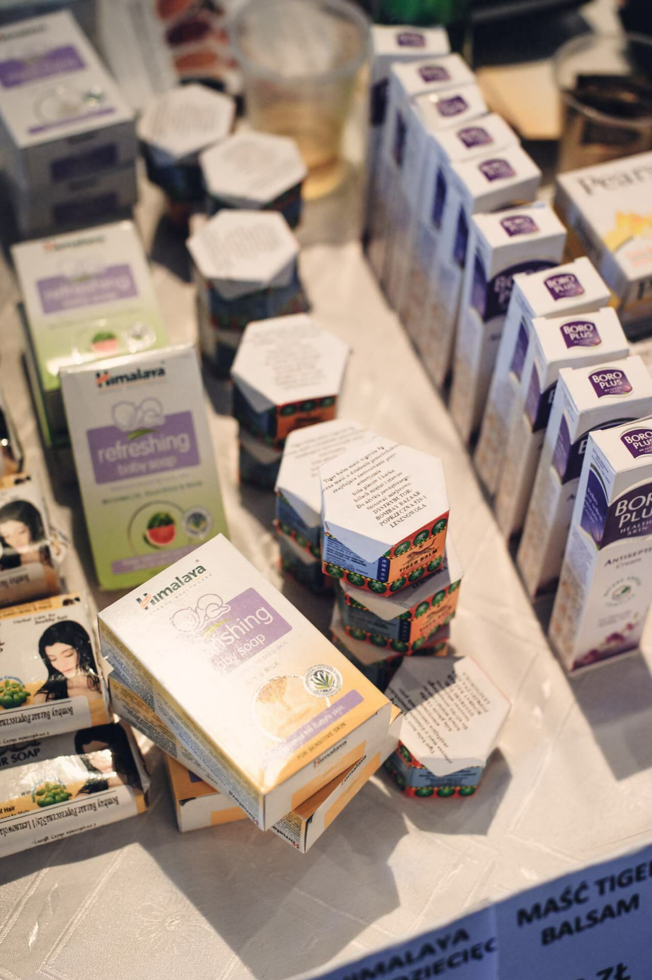 A display of various skin care and wellness products, including boxes of soaps, refreshing wipes and body lotions. On a table covered with a white tablecloth, neatly arranged items relate to the culinary fair, showcasing various brands and colorful packaging designs. 