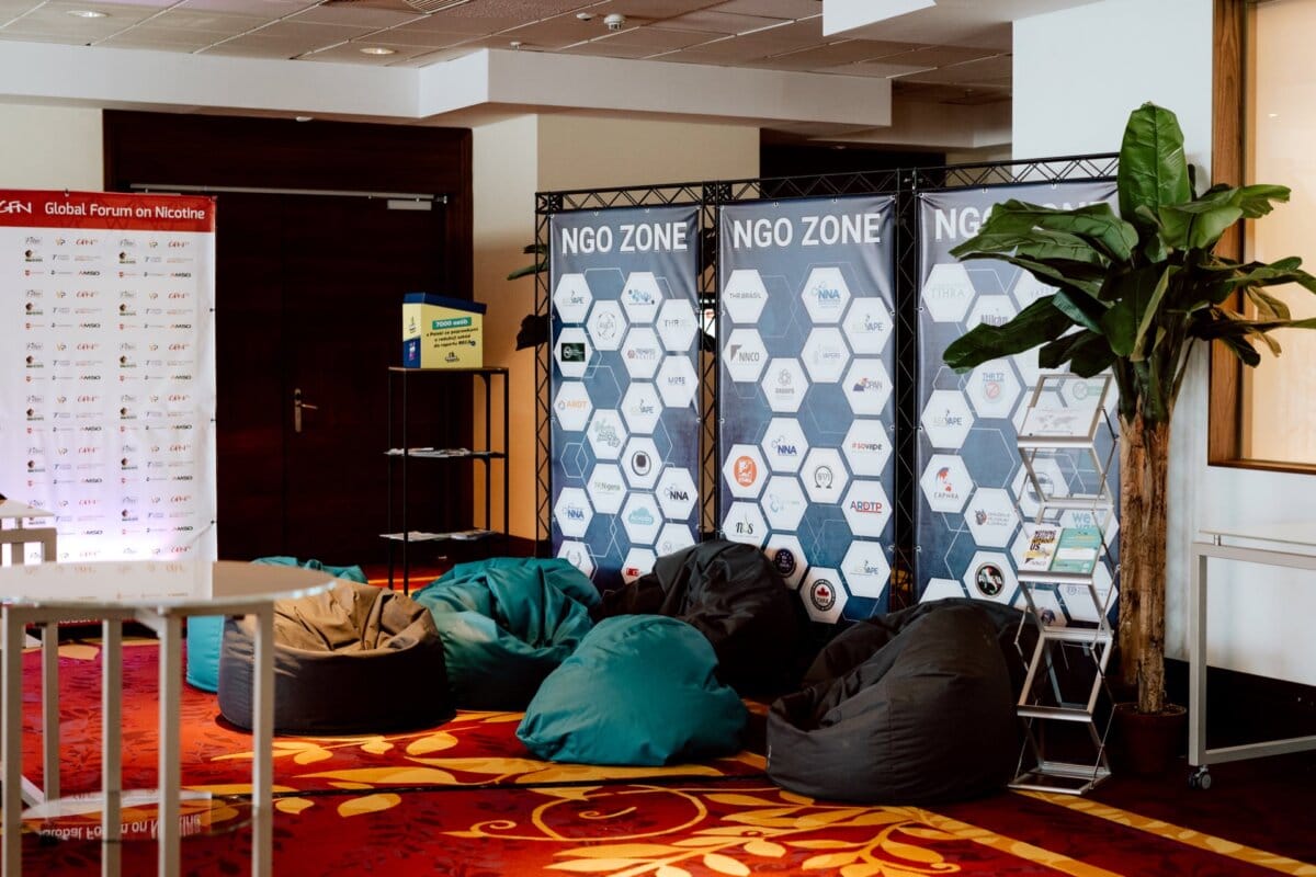 In the conference area, there is a section labeled "NGO Zone" with three vertical panels bearing hexagonal organization logos. The space is furnished with turquoise and black bean bags, a tall green plant and a bookcase. To the left stands a branded backdrop, perfect for any photographer at conferences.  