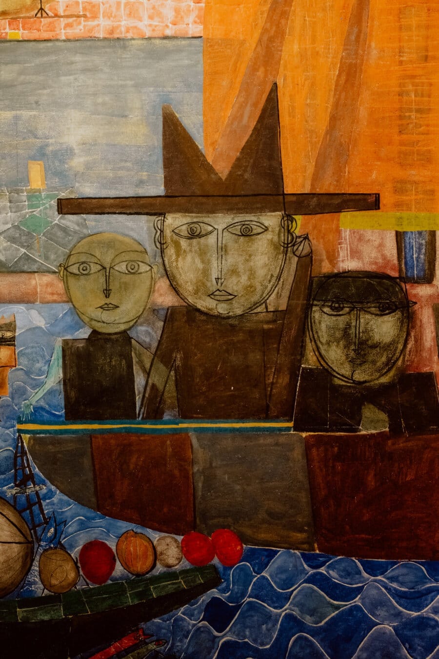 Colorful abstract painting depicting three human figures with simple geometric shapes and faces, sailing a boat on a rolling blue sea. The central figure wears a pointed hat. The background shows a patchwork of different colored sections, creating a whimsical scene.  