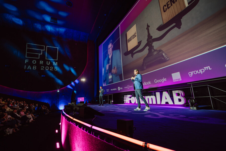 Prelegent prezentuje na scenie podczas wydarzenia FORUM IAB 2025, z dużym ekranem wyświetlającym skalę oznaczoną "Marcas" i "Centro" oraz publicznością siedzącą w ciemnym audytorium.