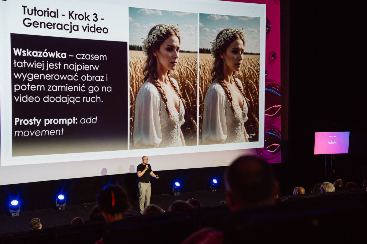 Prezenter przemawia do publiczności w teatrze, stojąc przed dużym ekranem wyświetlającym slajd instruktażowy na temat generowania wideo, z dwoma zdjęciami kobiety na polu i tekstem w języku polskim.
