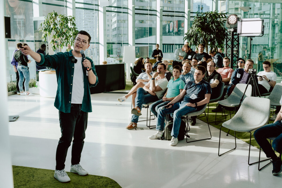 fotograf startupow rotunda reaktorX 35 Ein Mann, der vor einer Gruppe von Menschen in ein Mikrofon spricht.