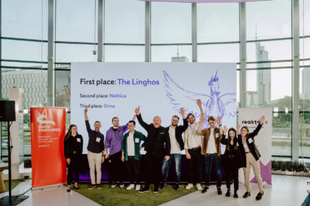 fotograf startupow rotunda reaktorX 81 Grupa ludzi stoi uśmiechnięta i świętuje przed dużym ekranem ogłaszającym zwycięzców konkursu. Na ekranie czytamy: "Pierwsze miejsce: Linghos; Drugie miejsce: Nethica; Trzecie miejsce: Dima.