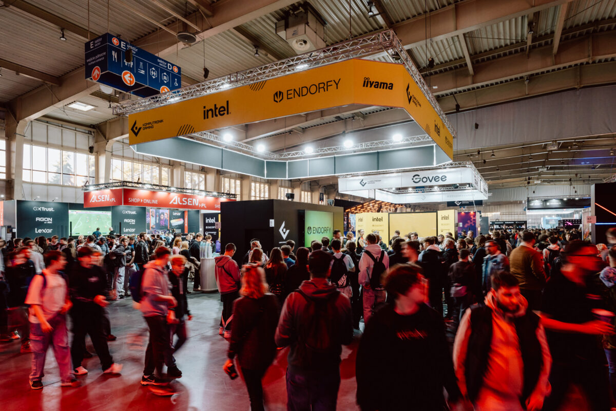 Eine große Menschenmenge läuft durch eine überfüllte Ausstellungshalle, die mit Ständen und Bannern von Technologiemarken wie Intel, Endorfy, Govee und Iiyama auf einer Technologie- oder Spielemesse gefüllt ist.