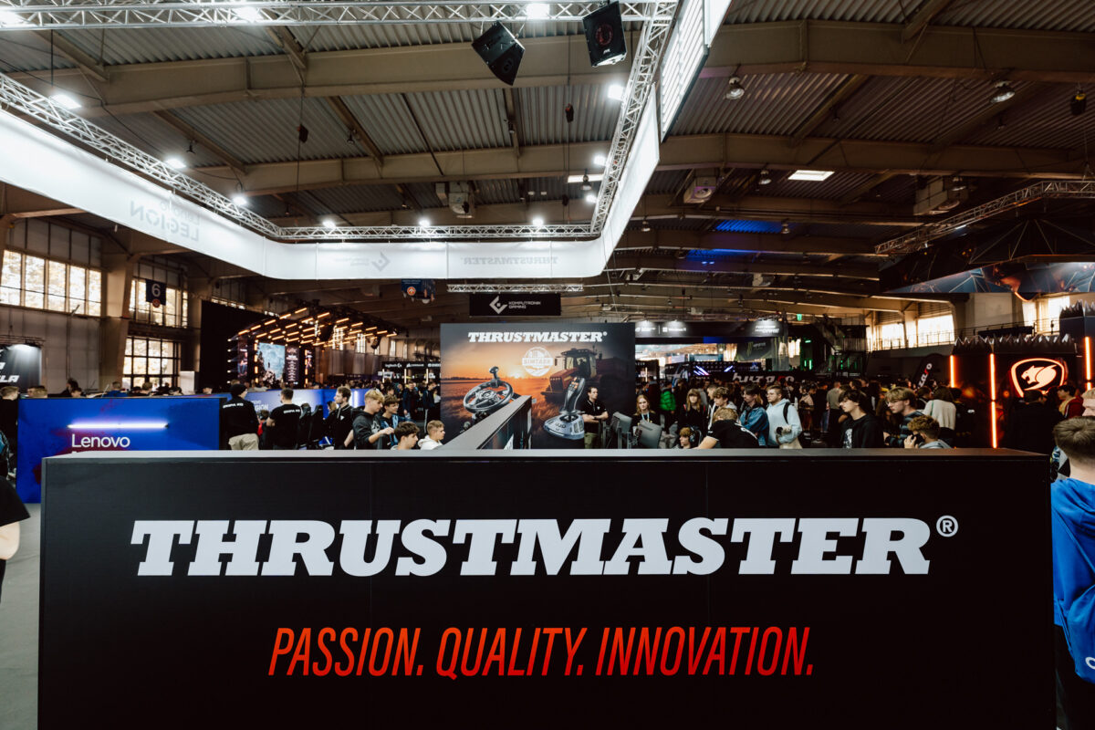 Eine große Menschenmenge versammelt sich auf der Spielemesse vor dem Thrustmaster-Stand mit dem Slogan "Passion. Qualität. Innovation." Helle Lichter und Markendisplays füllen die geräumige Halle. 