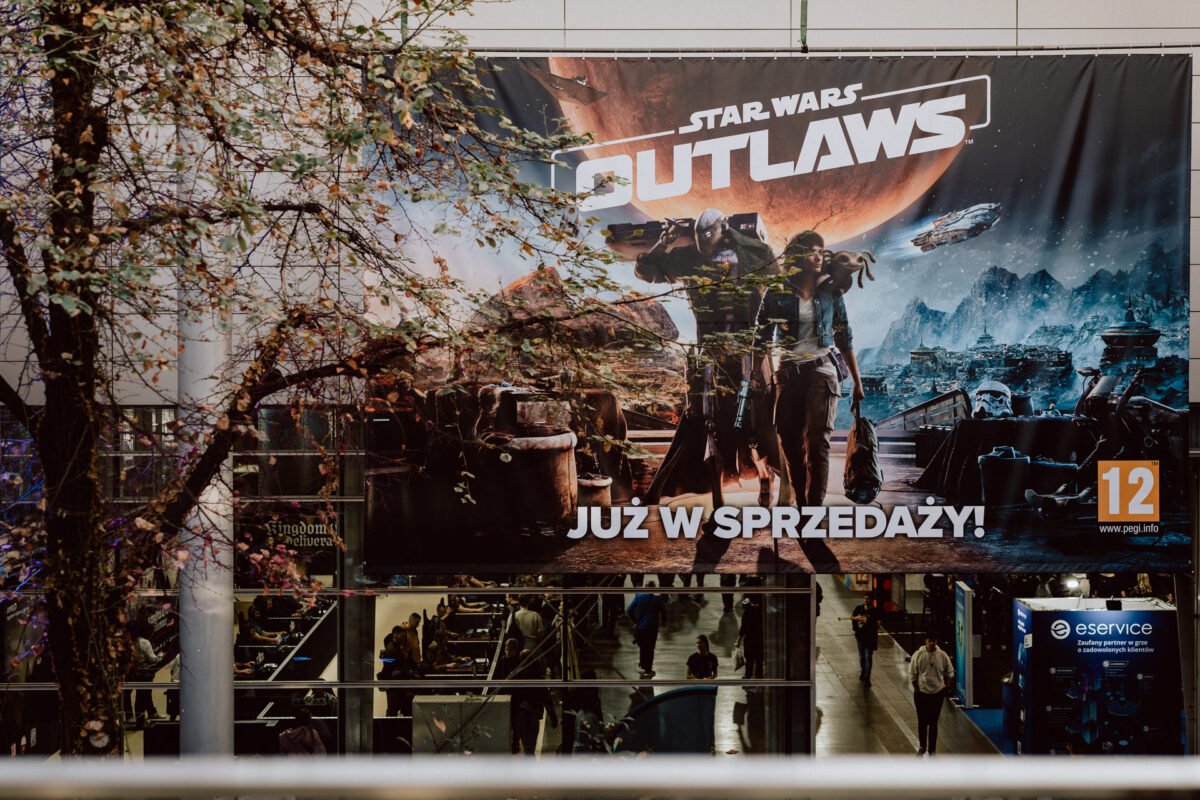 Großes Star Wars Outlaws-Videospielbanner mit Sci-Fi-Charakteren und Landschaft, das über dem Eingang der Kongresshalle angebracht ist; der Text lautet "Already on sale!" (Bereits im Verkauf!) auf Polnisch. 