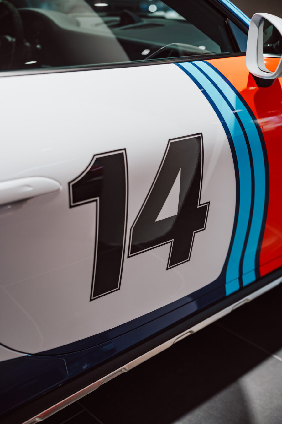 Nahaufnahme der Autotür mit der Nummer 14 mit großen schwarzen Ziffern auf weißem Hintergrund, mit blauen und roten Rennstreifen - ideal für die Werbung für die Eröffnungsveranstaltungen des Showrooms.