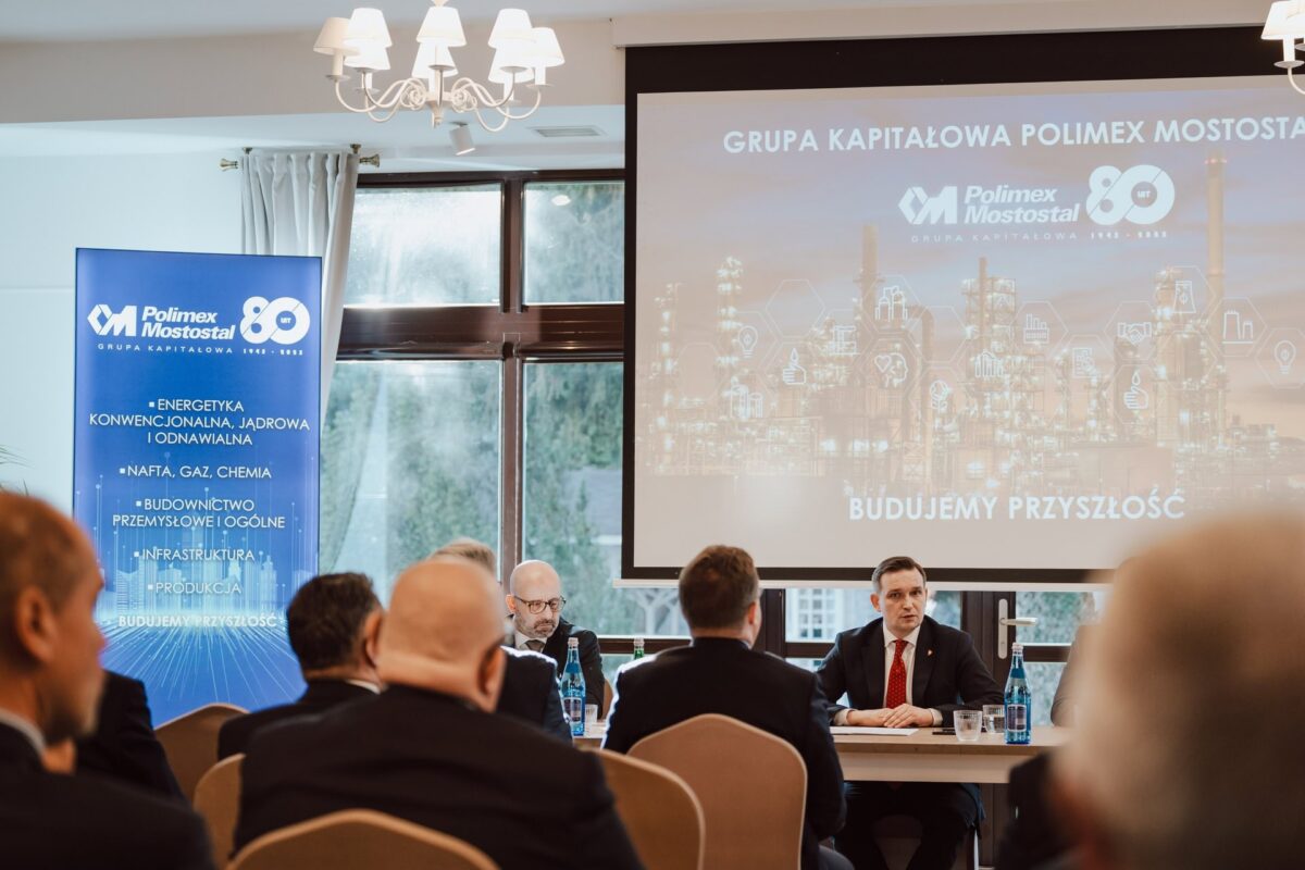 Panel dyskusyjny seminarium eksperckiego o bezpieczeństwie, prelegenci przy stole i ekran prezentacji