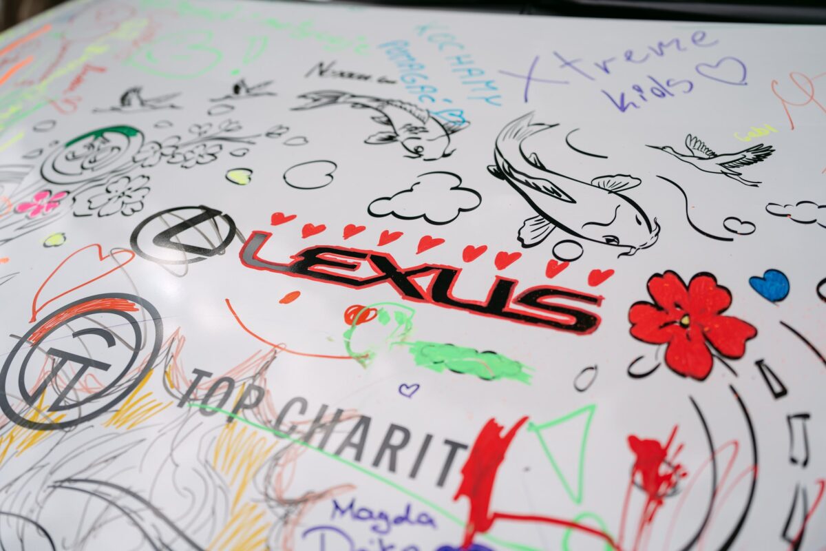 Logo Lexus otoczone rysunkami dzieci na masce auta, Lazy Sunday