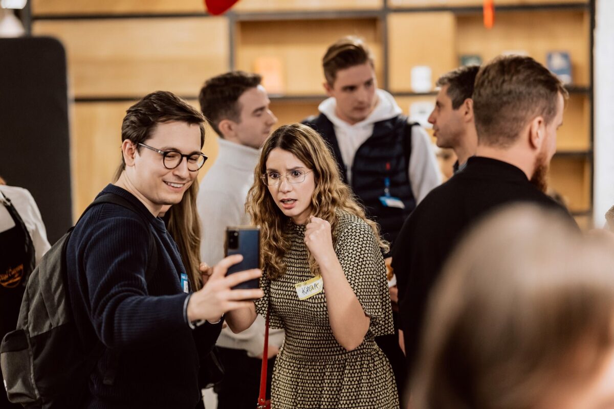 Uczestnicy gali Aulery 2022 przeglądają zdjęcia podczas networkingu