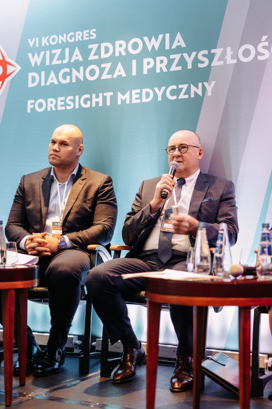 Wystąpienie panelisty na tle brandingu VI Kongresu Wizja Zdrowia 2022