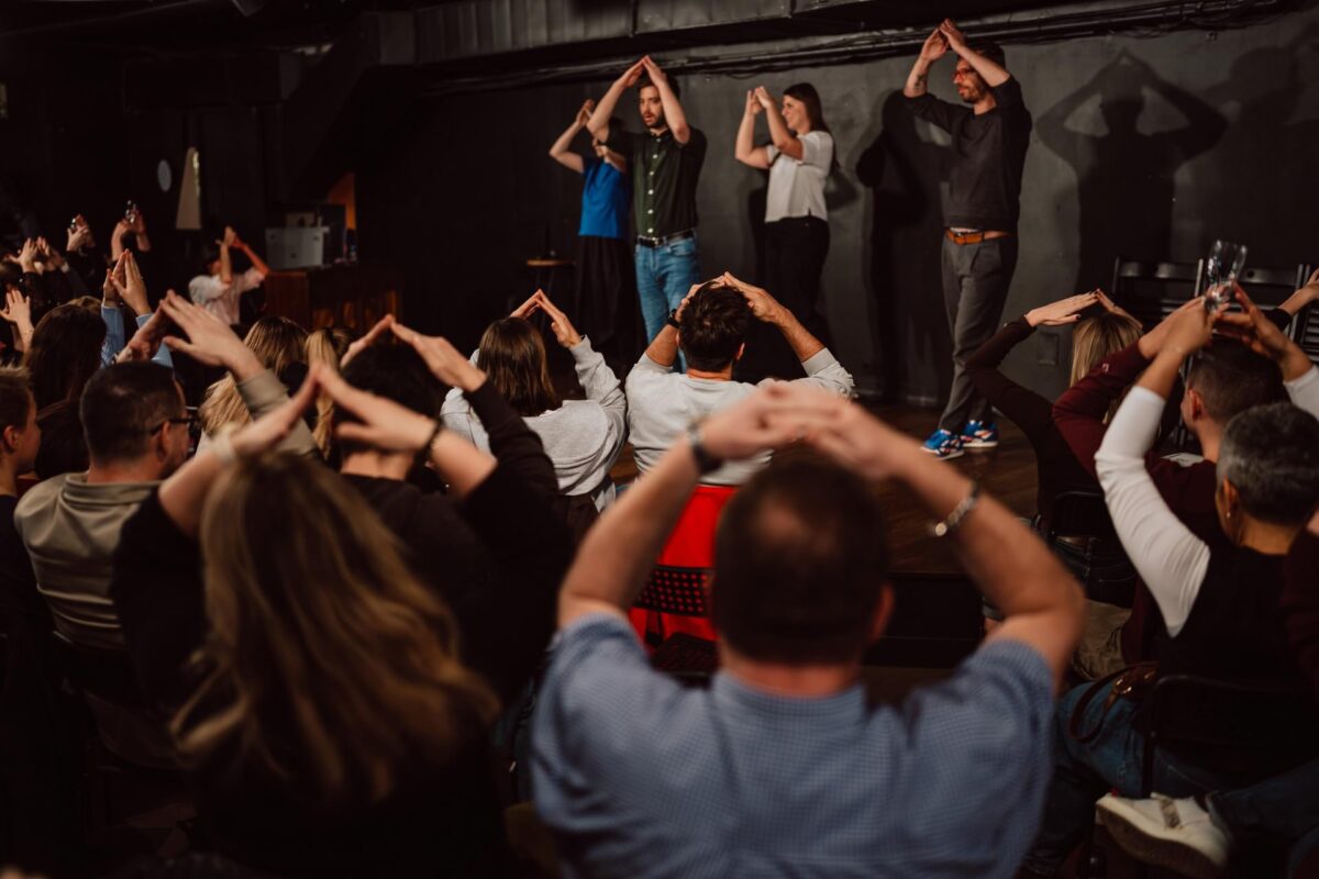 Publiczność powtarza gest komików podczas spektaklu impro w Klubie Komediowym