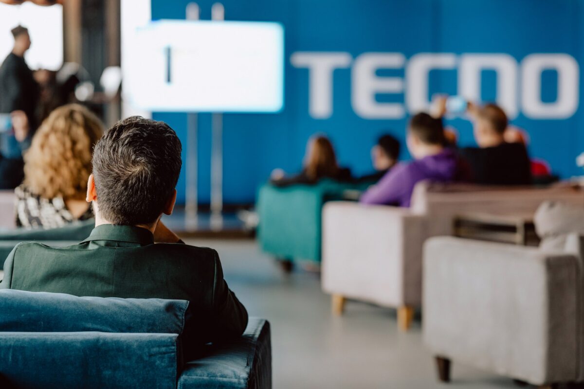 Goście premiery oglądają prezentację na tle brandingu Tecno