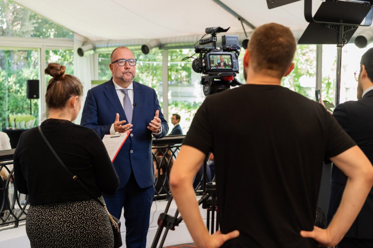 Ekspert udziela wywiadu przed kamerą telewizyjną w kuluarach konferencji