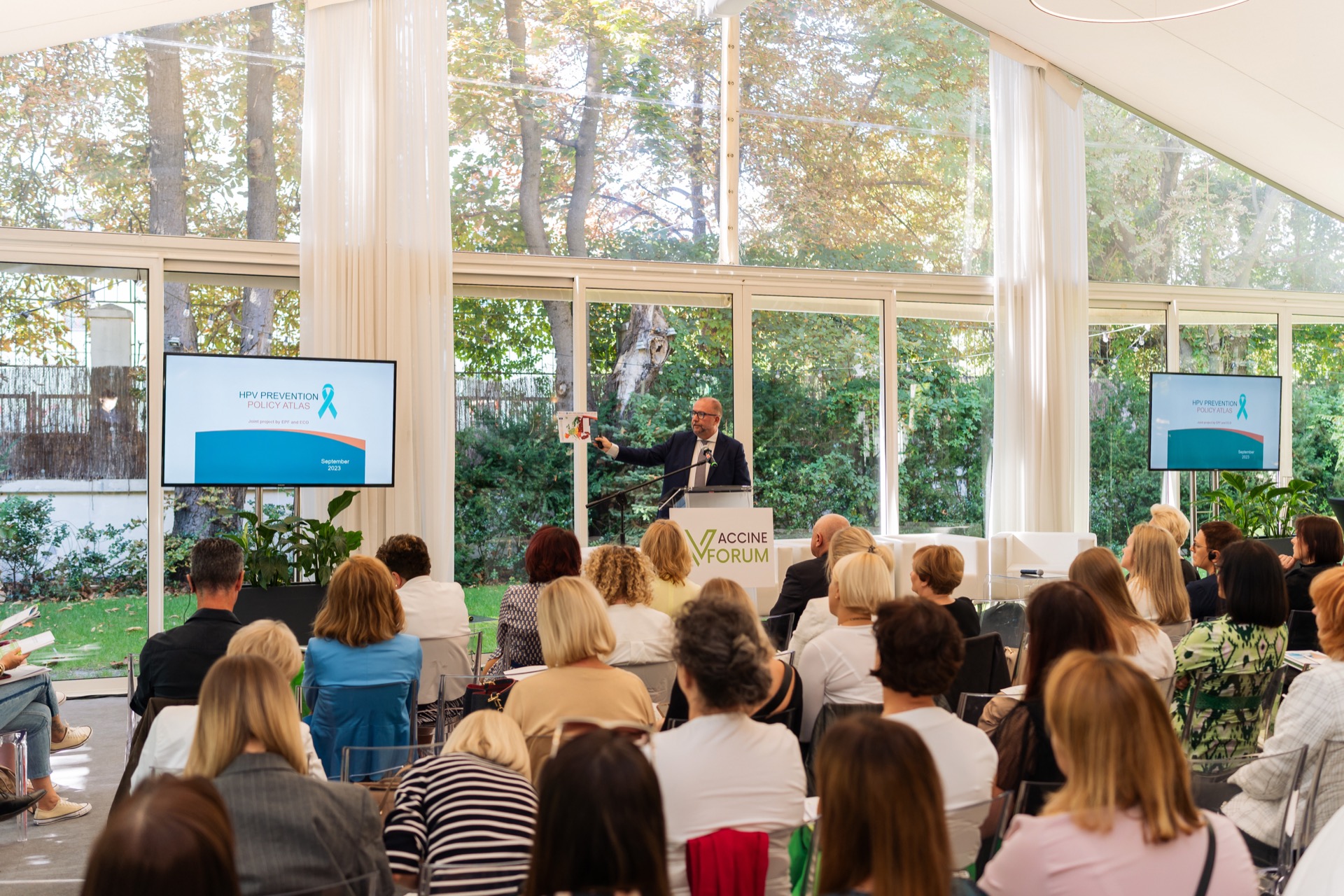 Prelegent przy mównicy Vaccine Forum omawia slajd, przed nim pełna widownia konferencji medycznej