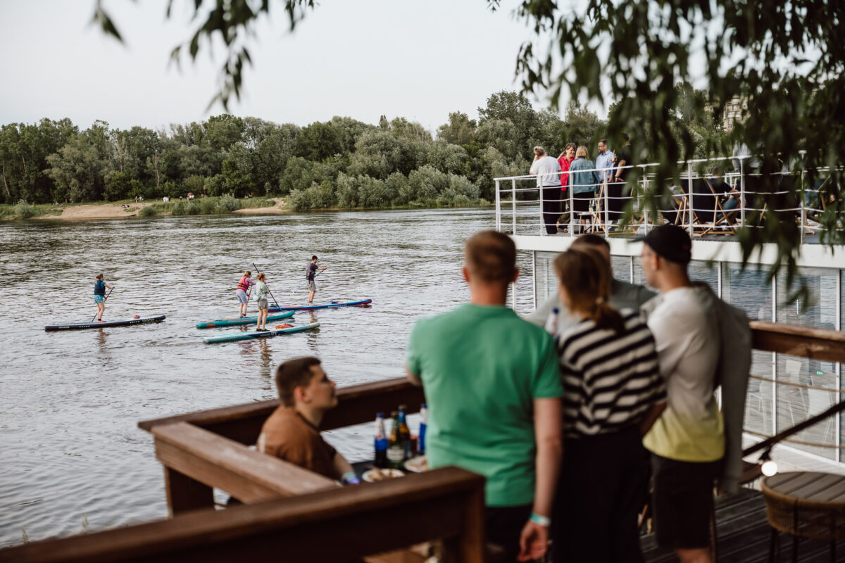 Guests at a company team event watching SUP boards float by on the Vistula