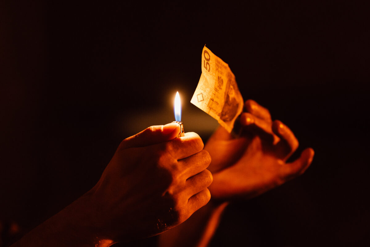 An illusionist's hands with a burning banknote in the dark