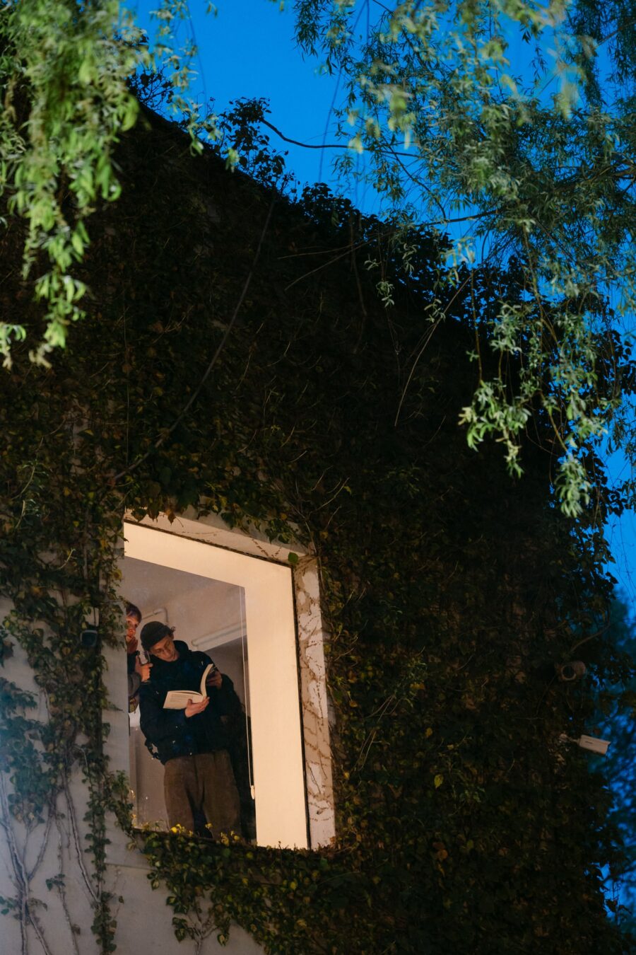 Gość czyta książkę w oknie nowej siedziby Instytutu Fotografii Fort o zmierzchu