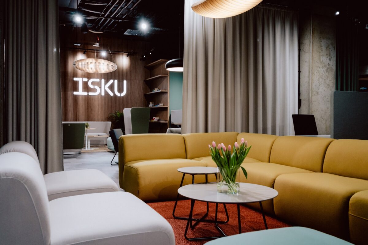 Showroom ISKU w Warszawie, strefa wypoczynkowa z żółtą sofą modułową i podświetlonym logo marki