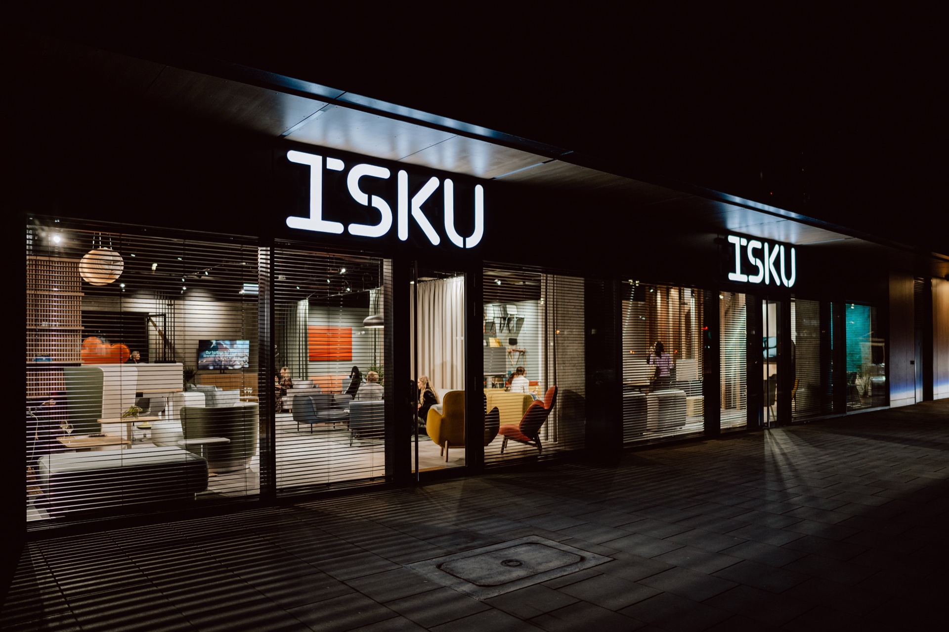 Witryna showroomu ISKU nocą, podświetlone logo marki nad przeszkleniami