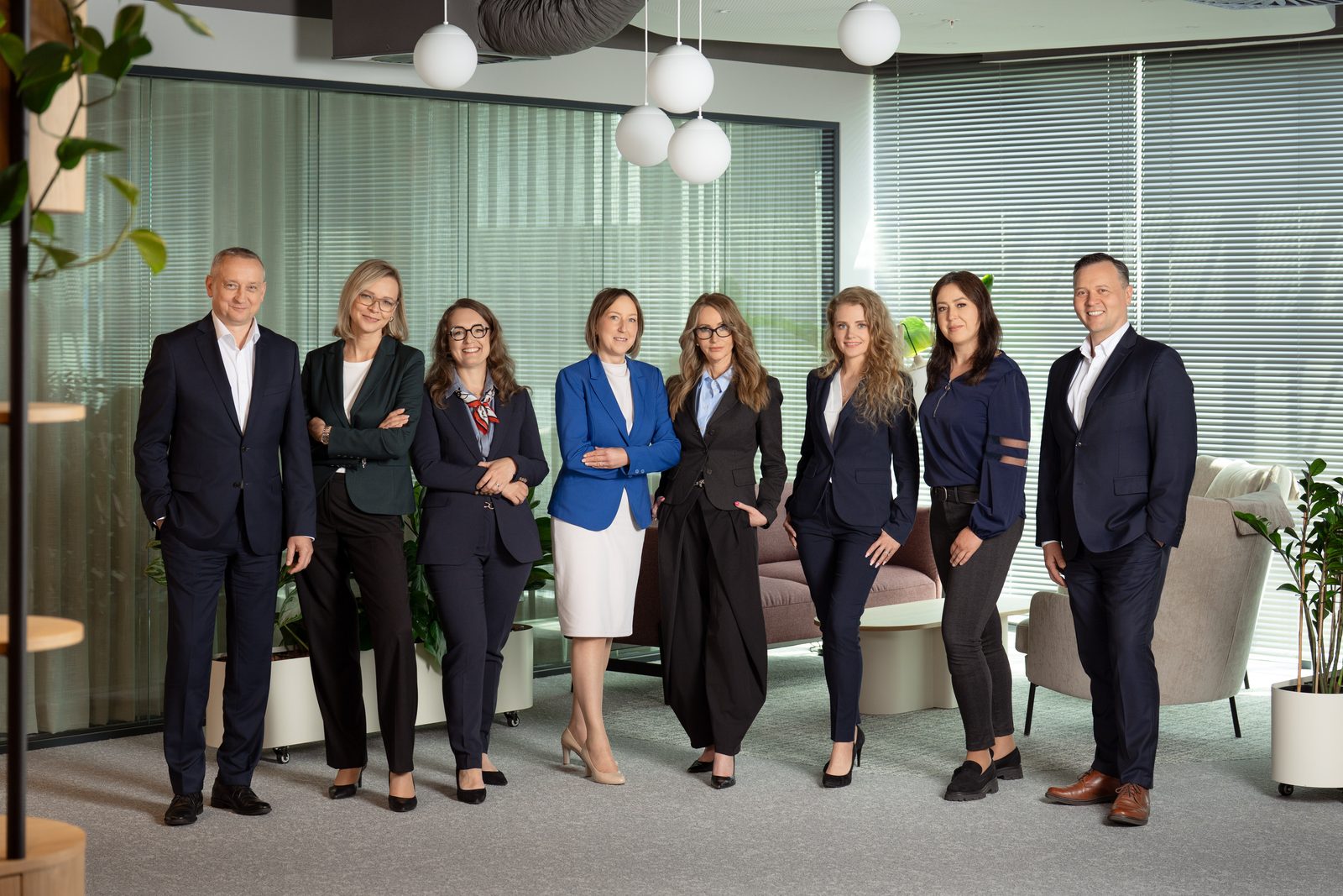 Gruppenfoto eines achtköpfigen Teams im Firmenbüro, aufgenommen bei einem Business-Shooting in Warschau.