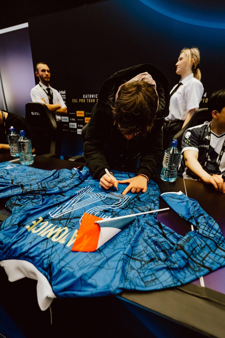 Zawodnik podpisuje koszulkę kibica przy stole autografów, IEM Katowice 2024