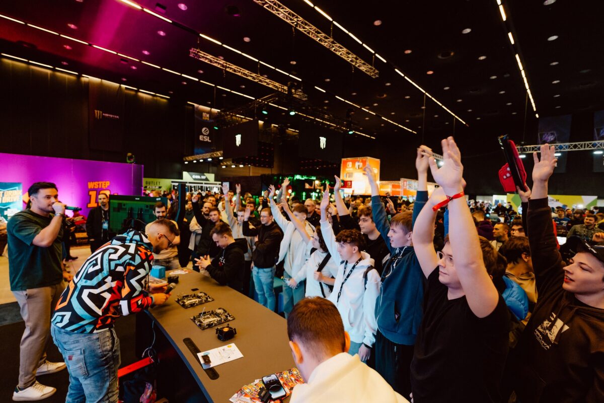 Uczestnicy konkursu składania PC podnoszą ręce przy stole na IEM Katowice 2024