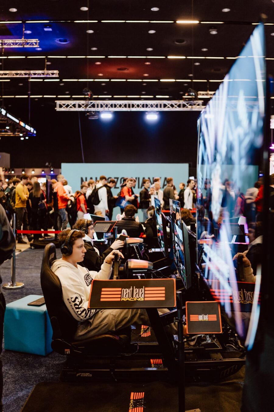 Strefa symulatorów wyścigowych z graczem za kierownicą w hali Expo, IEM Katowice 2024