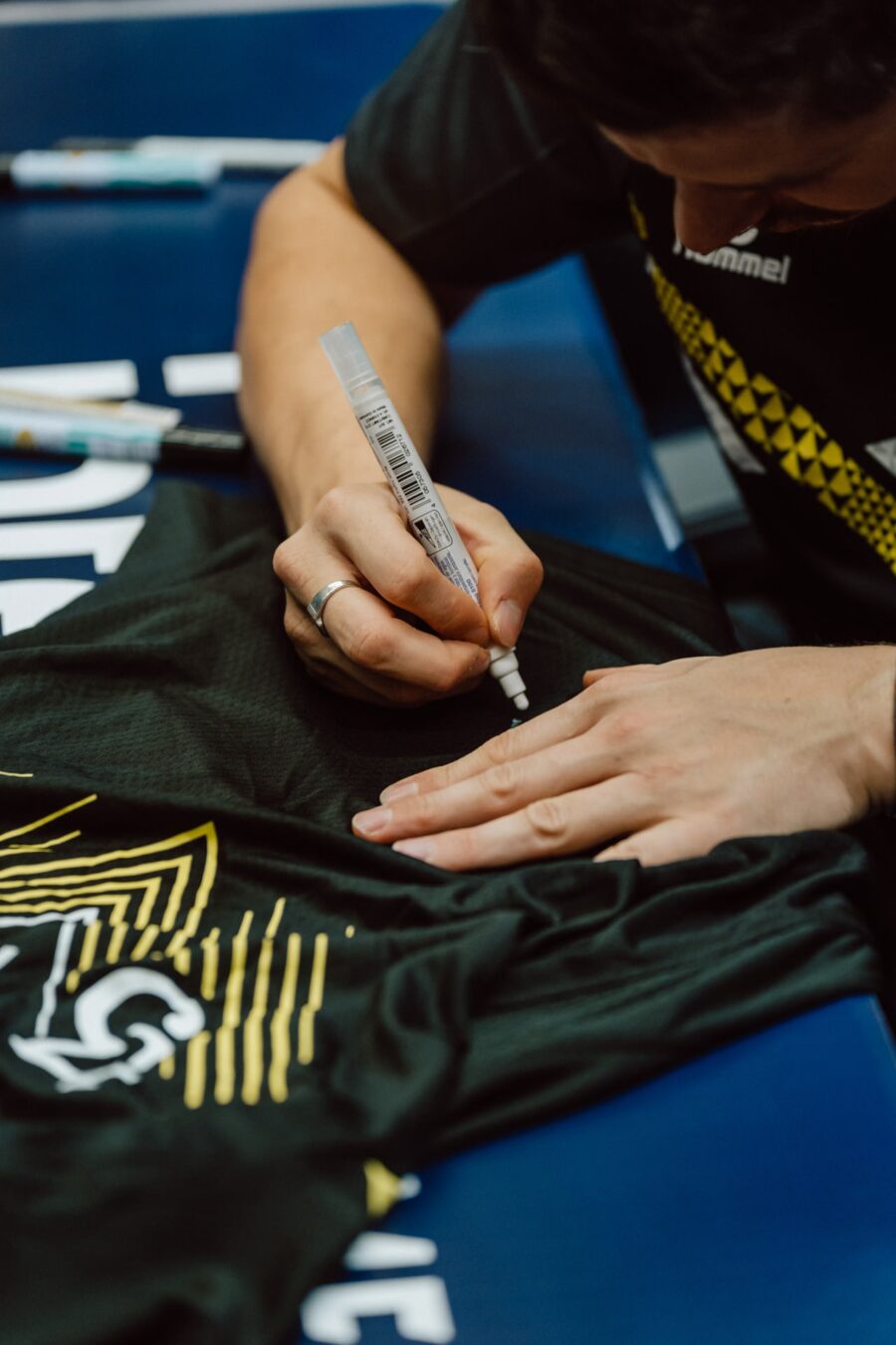 Zawodnik podpisuje koszulkę drużyny podczas sesji autografów na IEM Katowice 2025
